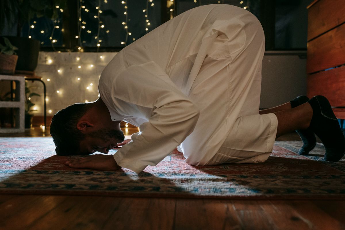 A Muslim man praying on a rug